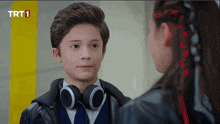 a boy wearing headphones looks at a girl with trt1 written on the bottom of the screen