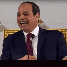 a man in a suit and tie is laughing into a microphone