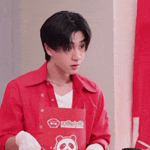 a young man wearing a red shirt and an apron with a panda on it