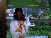 a woman holding an umbrella in the rain with a statue in the background