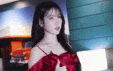 a woman wearing a red dress with a car in the background