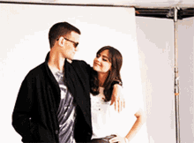 a man and a woman standing next to each other with the woman 's arm around the man 's shoulder