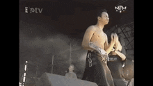 a man without a shirt is standing on a stage in front of a m & m sign