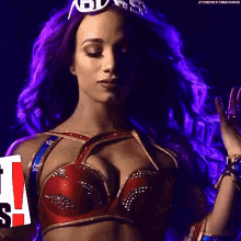 a woman with purple hair is wearing a red bra and holding a sign .