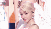 a woman with blonde hair is wearing a white dress and earrings .