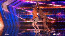a couple of people are dancing on a stage with the nbc logo in the background