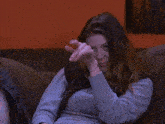 a woman sitting on a couch wearing a grey shirt and a black vest