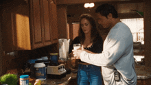 a man and a woman standing in a kitchen with a blender that says big bob