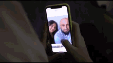 a person taking a picture of a man and a woman on their phone