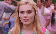 a close up of a woman 's face with a crowd of people in the background .