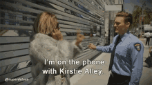 a woman talking on a cell phone next to a police officer who says " i 'm on the phone "