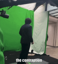 a man in a suit is standing in front of a green screen that says the contraption on it