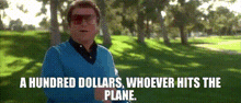 a man in a blue sweater is standing in a park with the words a hundred dollars whoever hits the plane below him