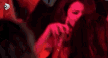 a group of people are dancing in a dark room with red lights behind them .