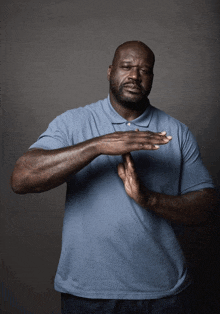 a man in a blue shirt is making a stop gesture