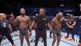 a referee stands between two fighters in a boxing ring