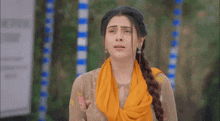 a woman with her eyes closed is wearing a yellow scarf around her neck and a yellow dress .