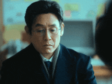 a man wearing glasses and a suit looks at someone