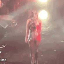 a woman in a red dress is walking on a stage
