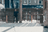 a man is leaning against a wooden fence in a city