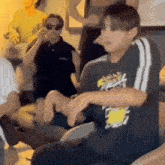a group of people are sitting on the floor in a room and a man is sitting in a chair .