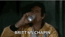 a man in a yellow jacket is drinking from a can and the words britt vs chapin are above him .