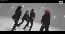 a group of women in black suits are dancing in front of a sign that says the k