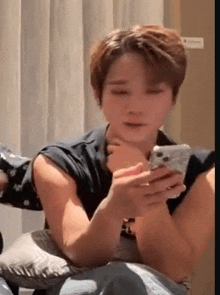 a man is sitting on a couch holding a cell phone in his hands .