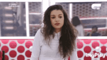 a woman with long hair and a white shirt is sitting in front of a red and white polka dot wall .