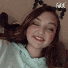 a young girl is smiling with her eyes closed and wearing a headband with balls on it .