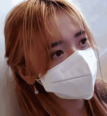 a woman wearing a white face mask and earrings