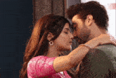 a man and a woman are kissing and the woman is wearing a pink shirt