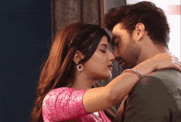a man and a woman are kissing and the woman is wearing a pink shirt