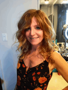 a woman with red hair is smiling in front of a light switch