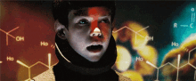 a young boy stands in front of a display of chemical compounds including oh and ho