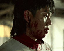 a man with blood on his face is wearing a white and red jacket