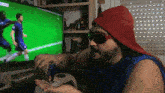 a man wearing sunglasses and a red hat is watching a soccer game