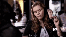 a woman is sitting at a table with her eyes closed and holding a fork in her mouth .
