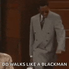 a man in a suit and tie is standing in front of a door and says `` dd walks like a blackman '' .