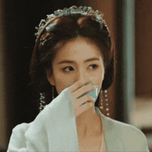 a woman with a crown on her head is drinking from a cup