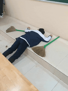a person is laying on the floor with two brooms on the floor