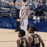 a basketball player with the number 15 on his jersey stands on the court