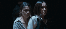 two women standing next to each other with their arms outstretched in the dark