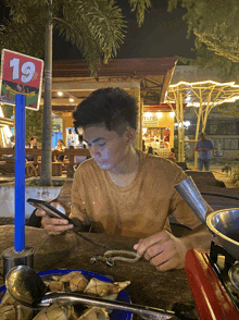 a young man sits at a table with a sign that says 19