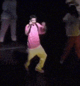 a boy in a pink shirt is dancing on a stage