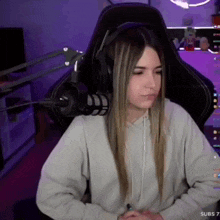 a girl wearing headphones is sitting in a gaming chair