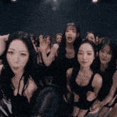 a group of women are standing in a dark room looking at the camera