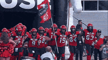 a group of football players are walking out of a tunnel wearing red uniforms with the number 19 on them
