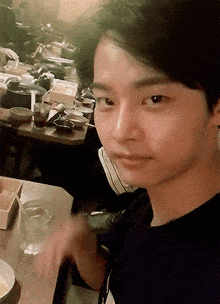 a young man is sitting at a table with a glass of water