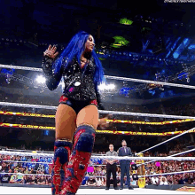 a woman with blue hair is standing in a wrestling ring with the word champions on the wall